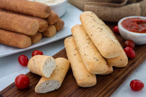 Savory breadsticks with garlic butter and sweet breadsticks in the background with cinnamon sugar