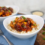 No-Fry Honey Sesame Chicken over rice in a white serving bowl