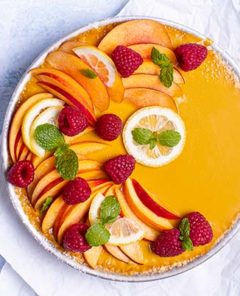 Peach & Mango No-Bake Pie decorated with fresh peach slices, lemon slices, raspberries, and mint