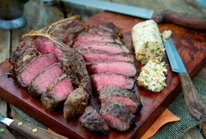 T-Bone Steaks with Savory Compound Butter sliced on a wooden cutting board