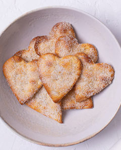 Overhead view of Heart-Shaped Sugar Cookies in a white shallow bowl on a white background