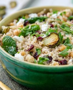 Closeup of Quinoa with Roasted Brussels Sprouts and Chickpeas in a green bowl with a gold fork