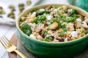 Closeup of Quinoa with Roasted Brussels Sprouts and Chickpeas in a green bowl with a gold fork