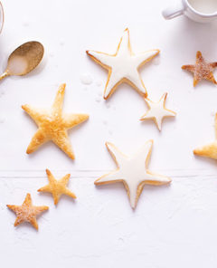 Vanilla Star Cookies on a white background with some cookies frosted and others left plain