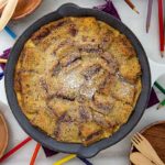 Sunbutter and Jelly Bread Pudding in a cast iron skillet with colored pencils and wooden utensils around it