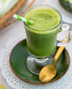 Overhead view of Mango Ginger Kale Smoothie with a green and white straw and green grapes in the background